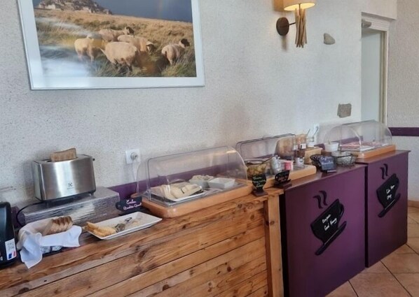 Montaje de un bufé de desayuno con una tostadora, pan y diversos alimentos sobre una encimera de madera.