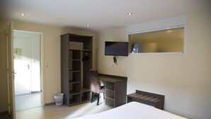 A bedroom with a bed, a desk, a chair, a TV, and a wardrobe. - Auberge de la Baie (Pontorson)