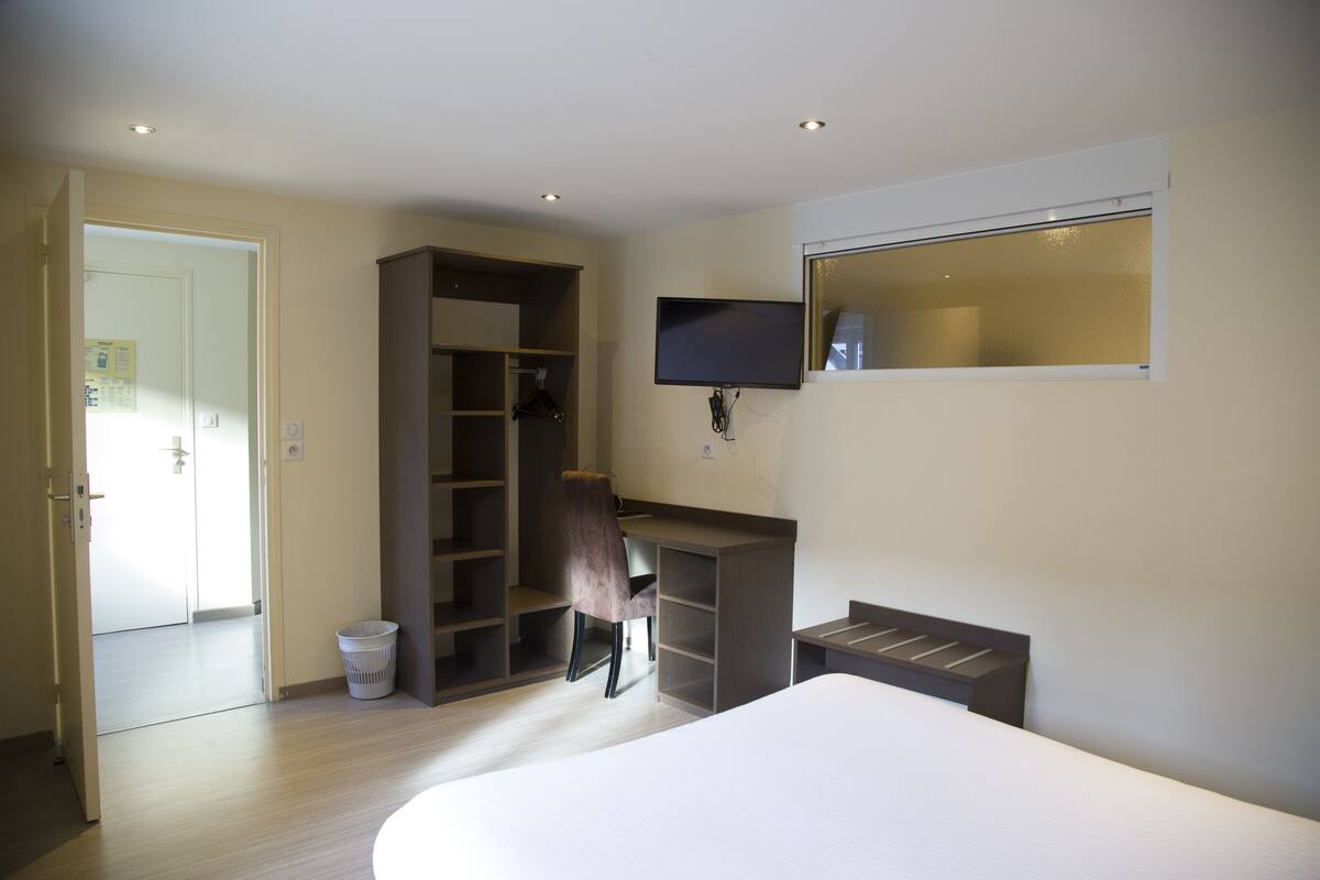 Un dormitorio con cama, escritorio, silla, televisor y armario.