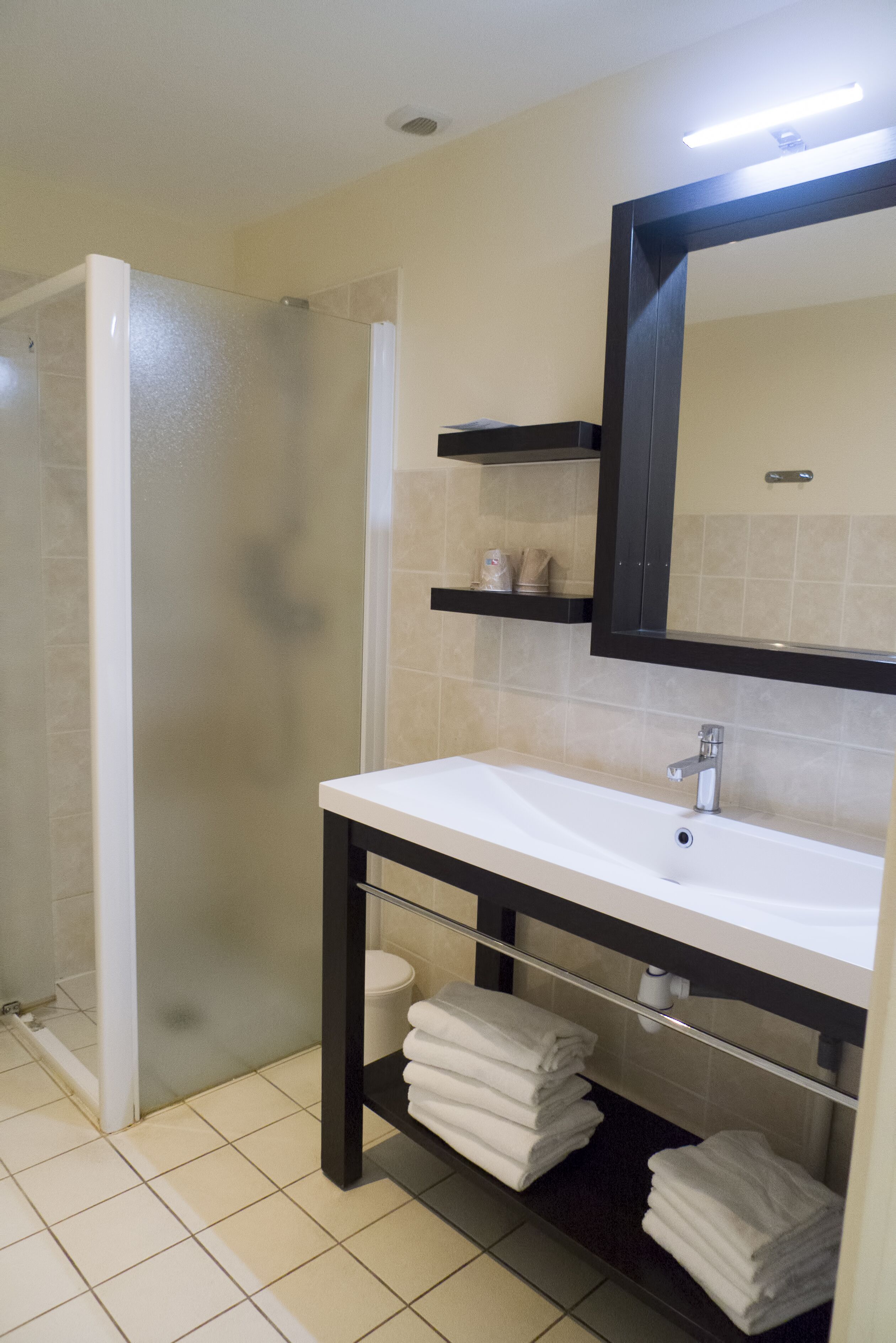 A bathroom with a white sink, a mirror, and a glass shower enclosure.
