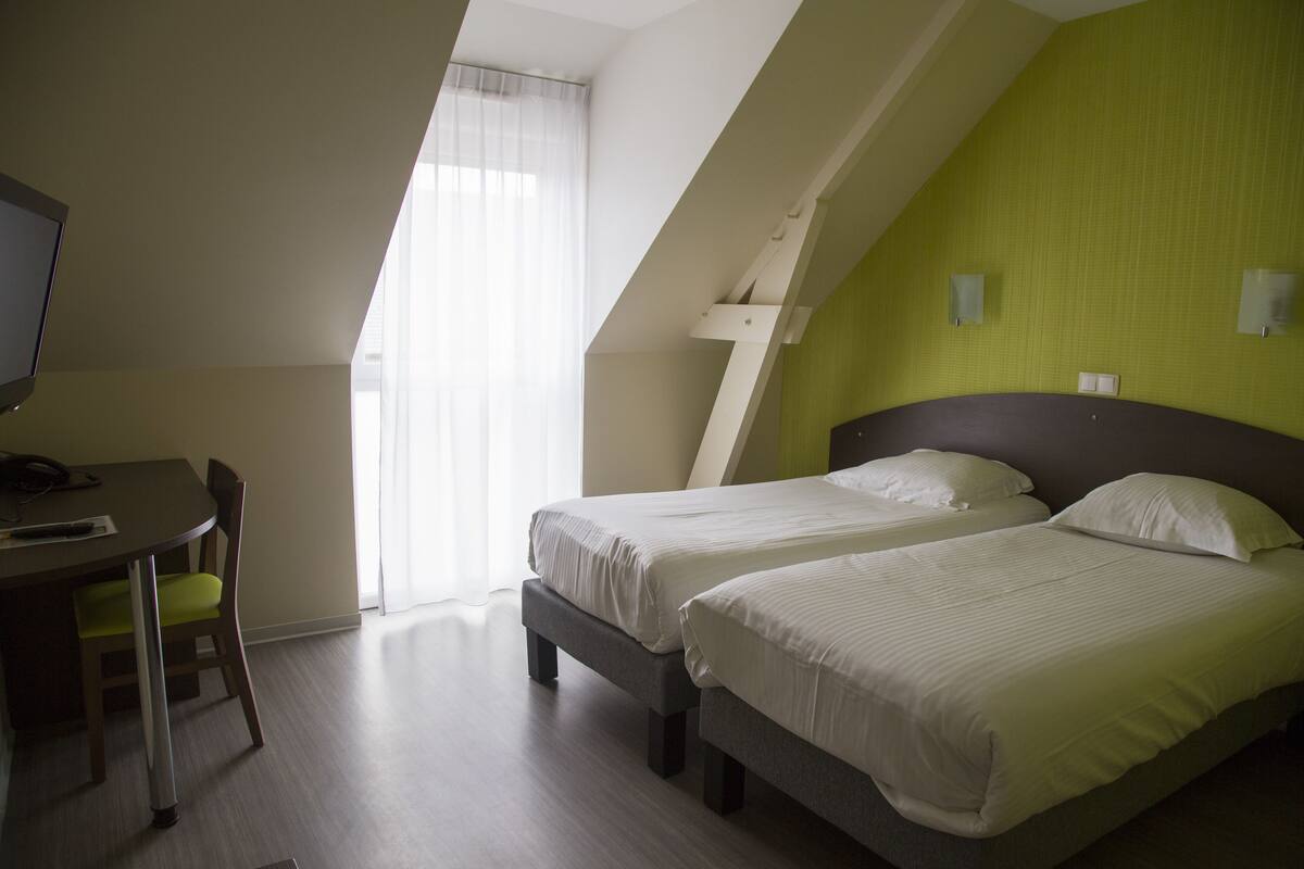 Habitación de hotel con dos camas, un escritorio y una silla.