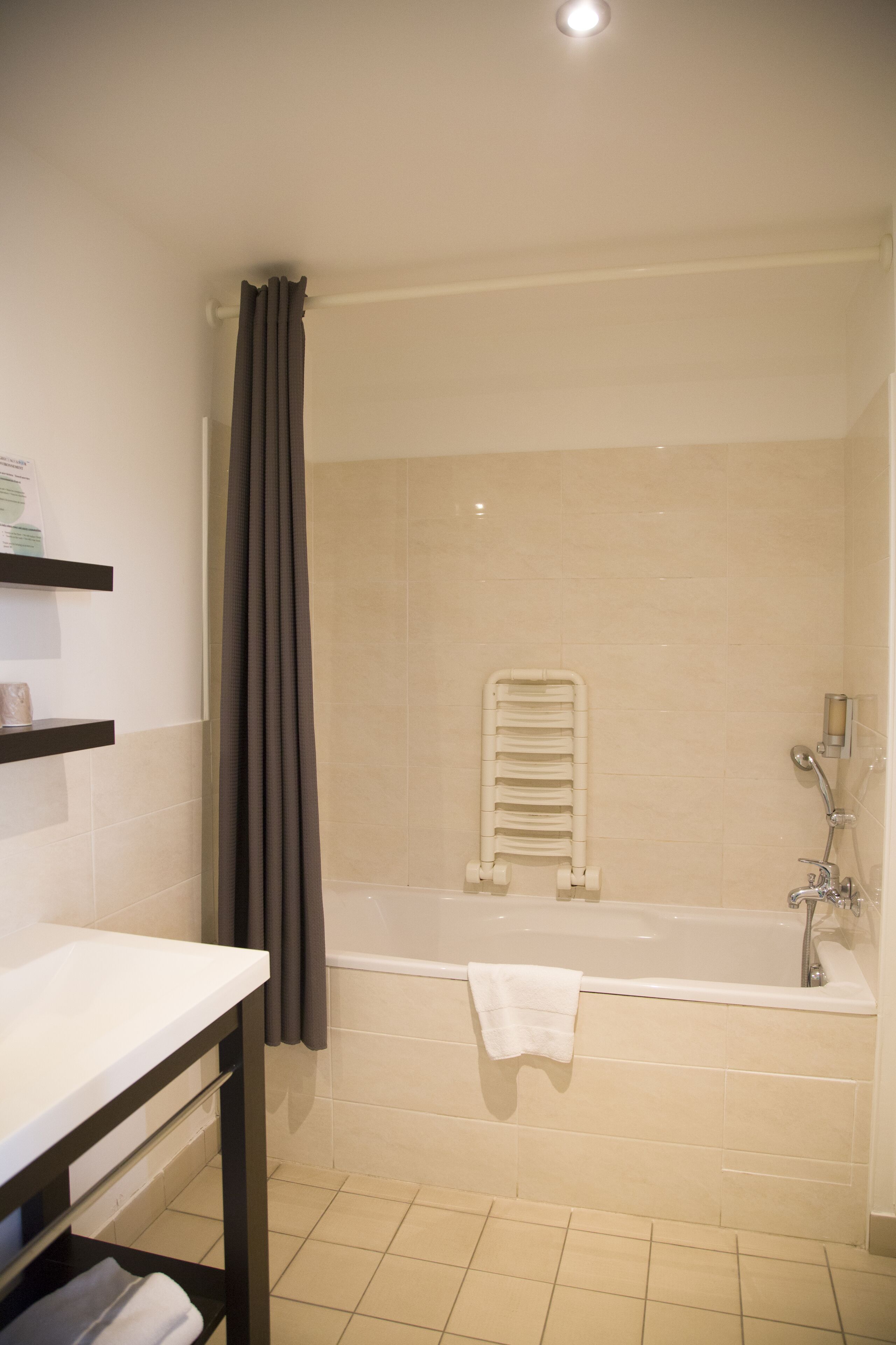 A bathroom with a bathtub, a towel rack, and a shower curtain.