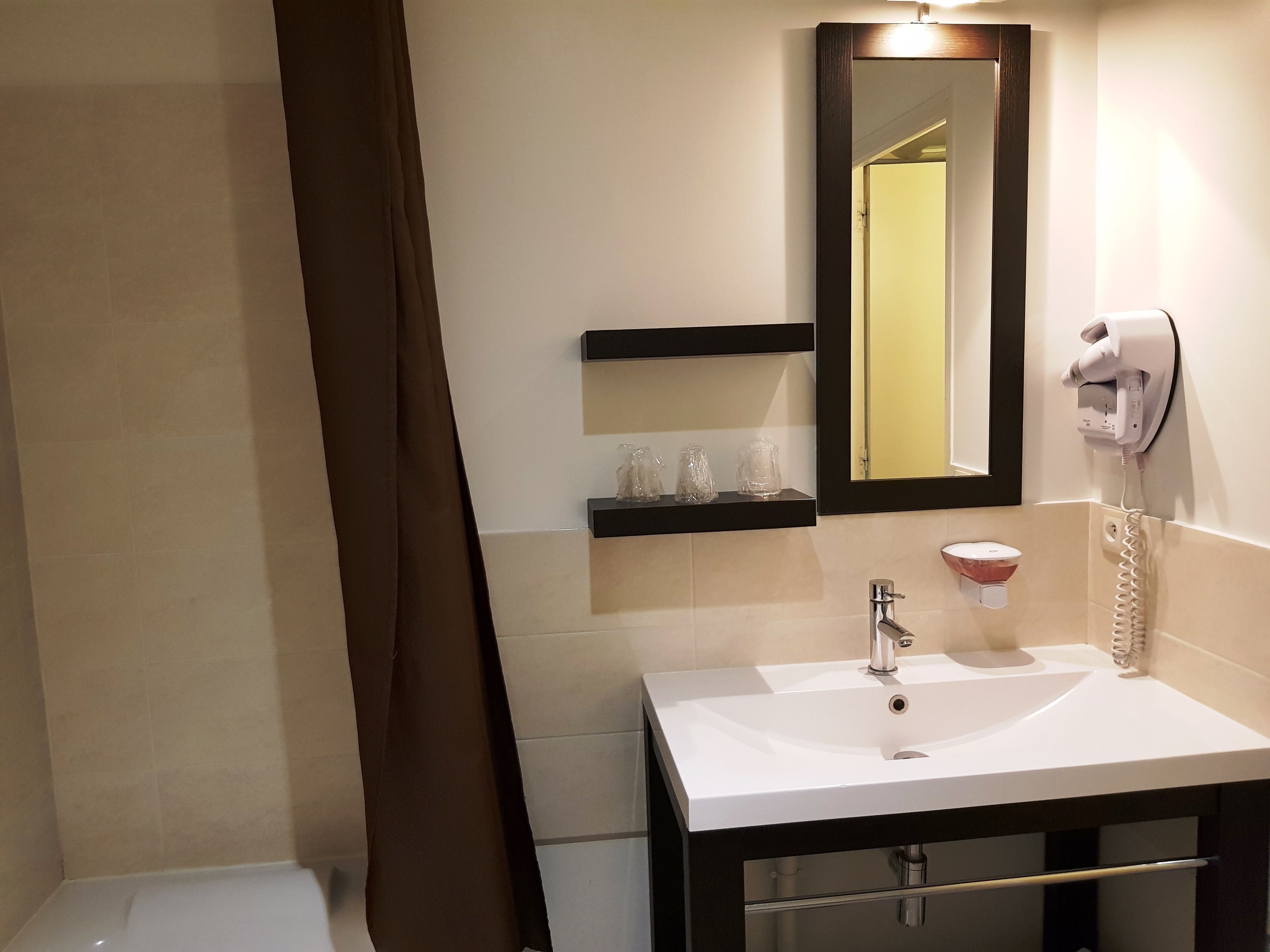 A bathroom with a white sink, a mirror, a hairdryer, and a towel rack.