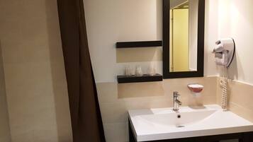 A bathroom with a white sink, a mirror, a hairdryer, and a towel rack.