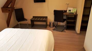 Ein Schlafzimmer mit einem Bett, einem Schreibtisch mit Stuhl, einer Bank und einem Fernseher an der Wand.