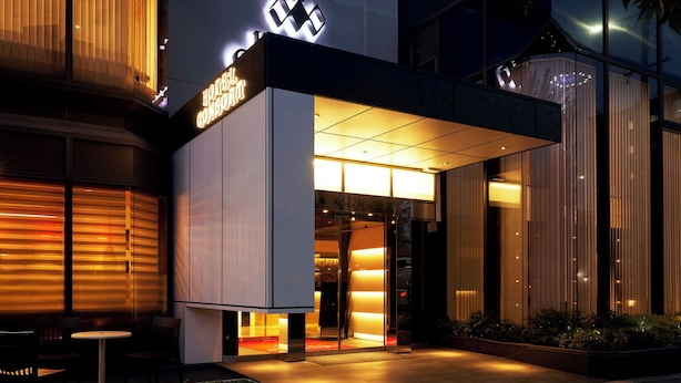 A modern hotel entrance with a prominent sign, a glass facade, and outdoor seating. - Hotel Consort Shin-Osaka (Osaka)