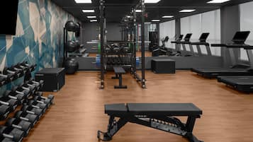 A gym with weightlifting equipment, treadmills, and a bench.