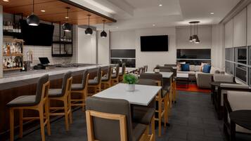 A modern kitchen with bar seating, a dining area, and a living space with a sofa and coffee table.