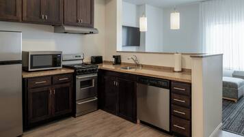 A modern kitchen with dark wood cabinets, stainless steel appliances, a granite countertop, and a large mirror above the sink.
