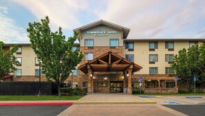 A hotel with a stone facade, a covered entrance, and a sign reading 'Towneplace Suites by Marriott.'
