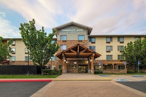 A hotel with a stone facade, a covered entrance, and a sign reading 'Towneplace Suites by Marriott.'