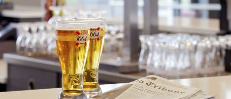 A bar setting with two glasses of beer, a newspaper, and a coffee machine.