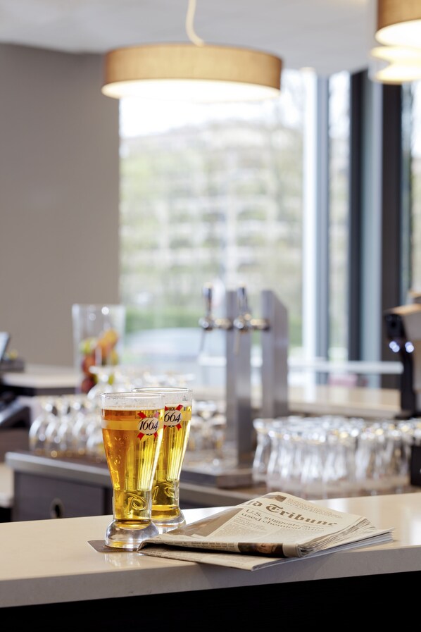 A bar setting with two glasses of beer, a newspaper, and a coffee machine.