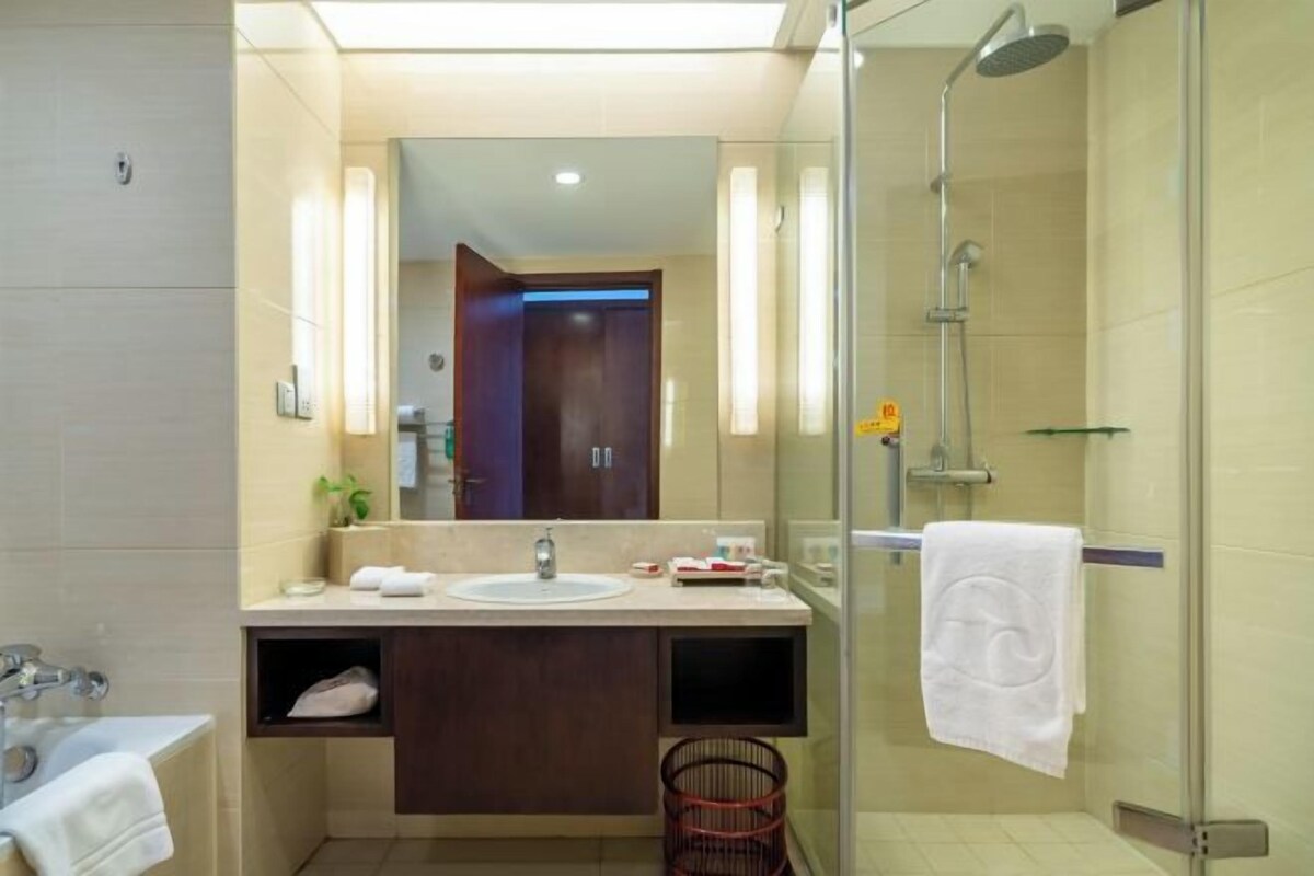 Un baño moderno con un espejo grande, un lavabo, una ducha y un perchero para toallas.