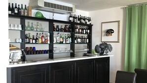 A bar area with shelves of liquor bottles and glasses, a coffee machine, and a framed skull decoration. - Luna di Marzo (Volastra)