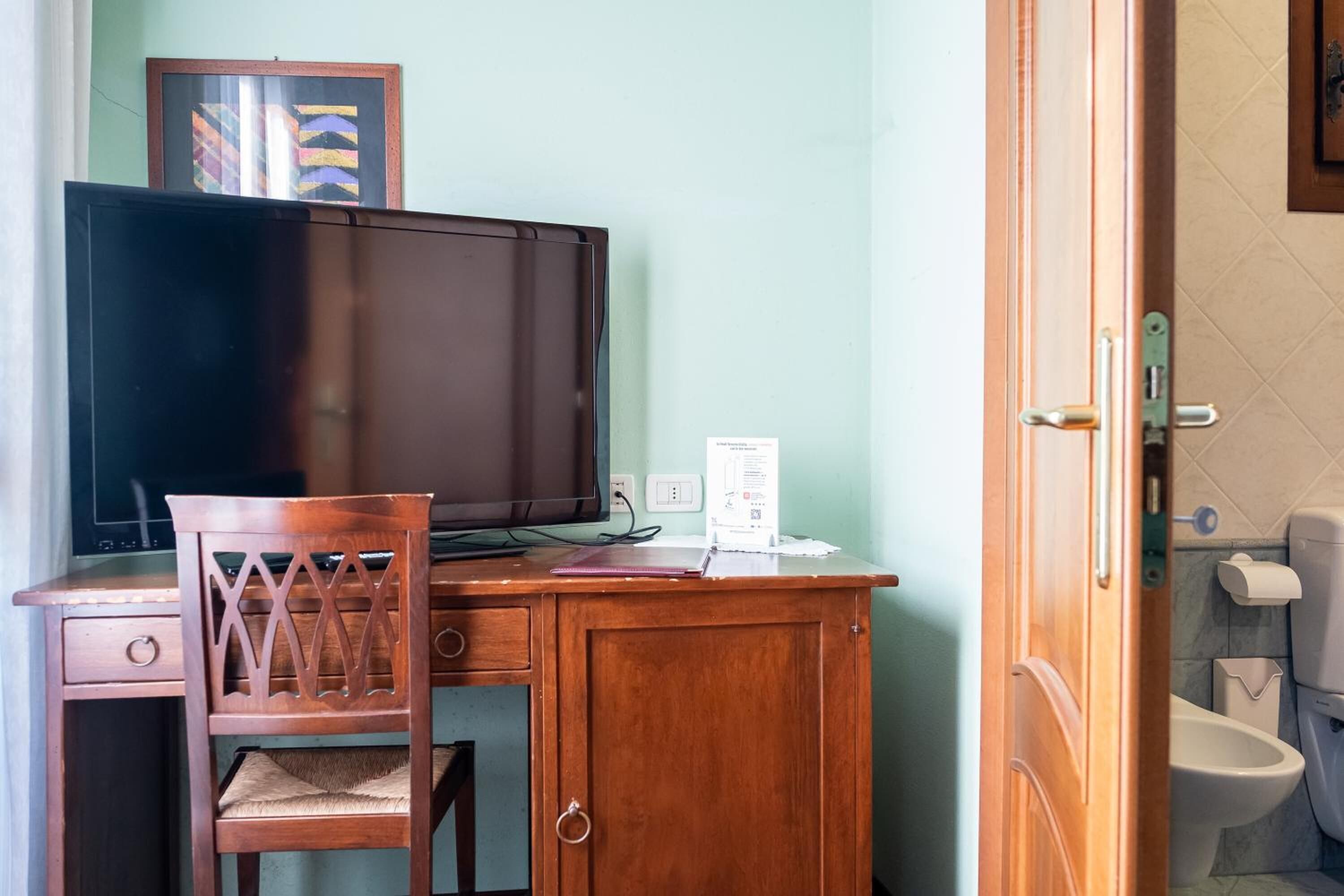 Un escritorio de madera con un televisor, una silla y un mueble auxiliar.