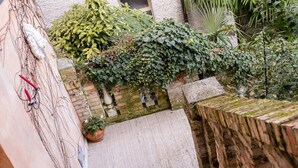 A narrow staircase with a brick wall on one side and a wooden fence on the other, leading to a garden area with various plants and a brick wall. - Principato di Ariis (Rivignano Teor)