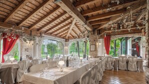 A restaurant with wooden beams, tables set for dining, and natural light from large windows. - Principato di Ariis (Rivignano Teor)