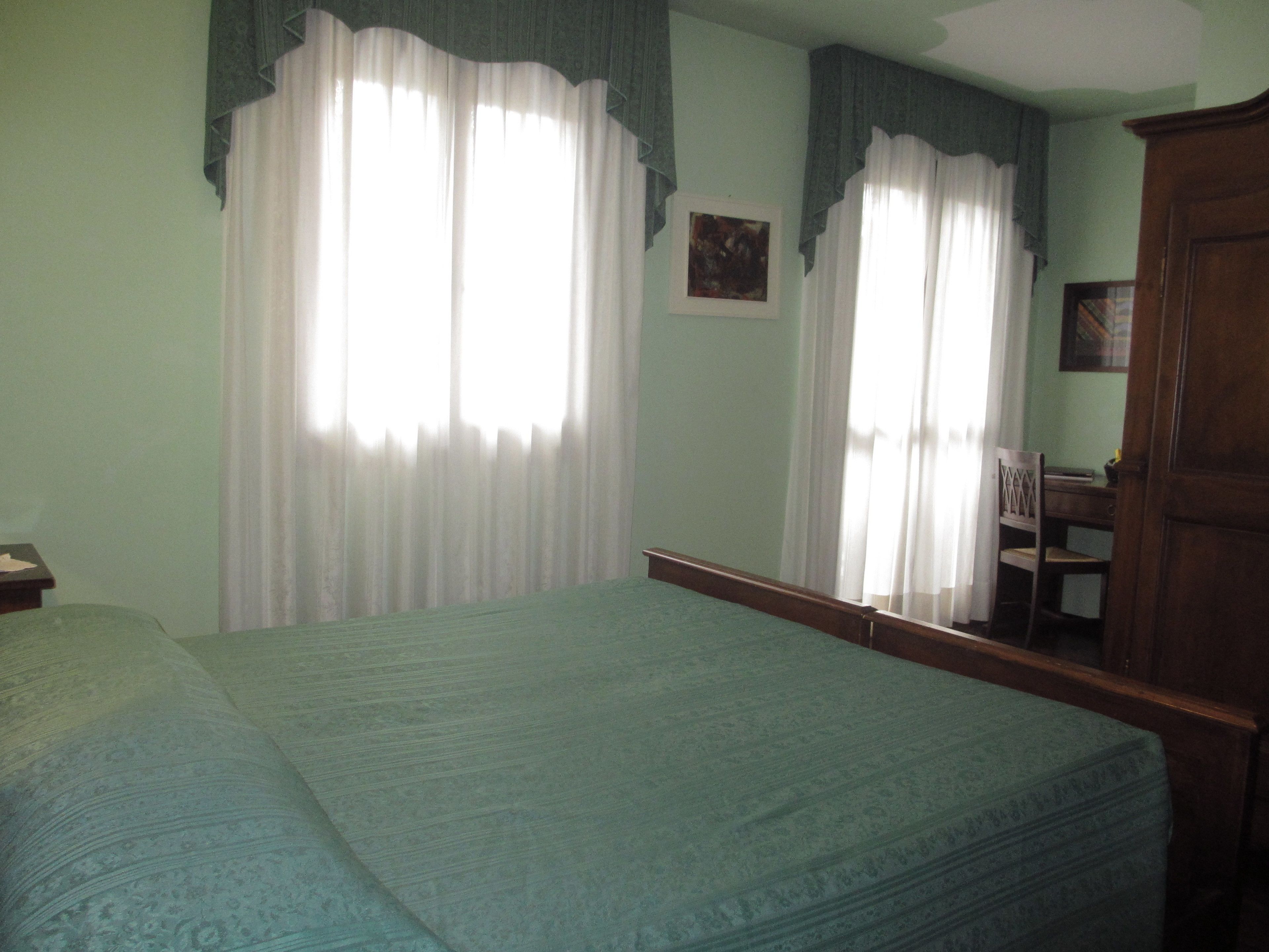 Una habitación con una cama, un armario de madera y una silla.
