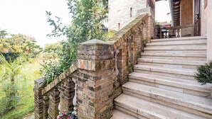 A stone staircase leading up to a building with a brick wall and a wooden door. - Principato di Ariis (Rivignano Teor)