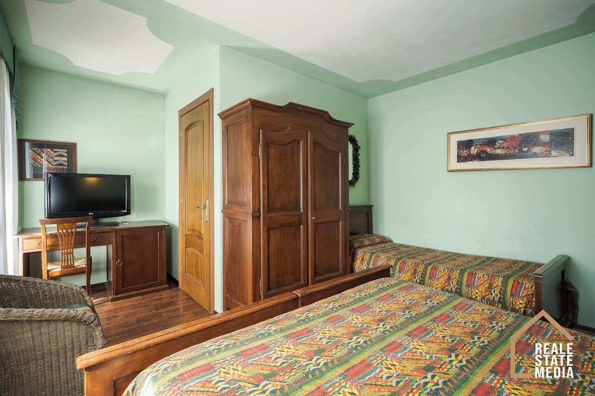 A room with a bed, a desk with a computer, a wardrobe, and a television.