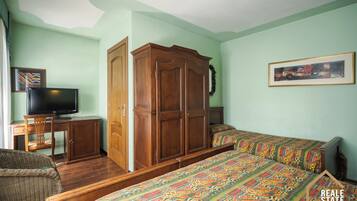 Una habitación con una cama, un escritorio con computadora, un armario y un televisor.