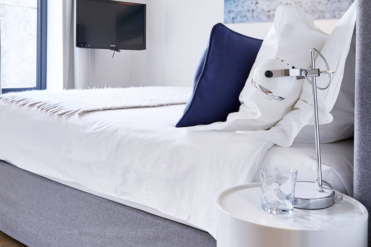 A hotel room with a bed, a TV, a nightstand, and a window.