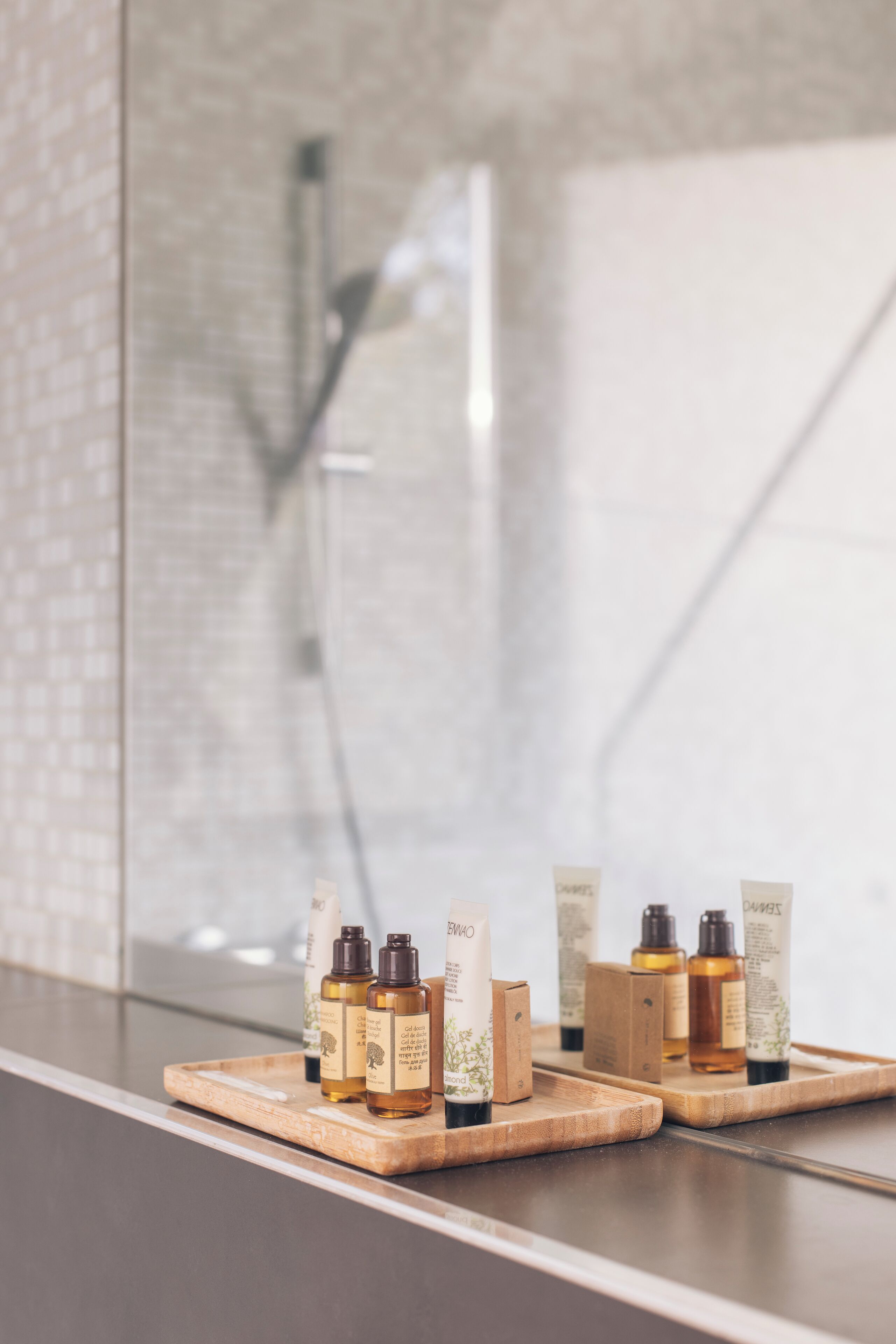 Une salle de bain dotée d’une douche à parois de verre et d’un plateau en bois contenant divers articles de toilette.