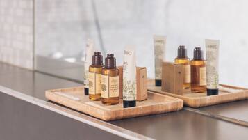 Une salle de bain dotée d’une douche à parois de verre et d’un plateau en bois contenant divers articles de toilette.