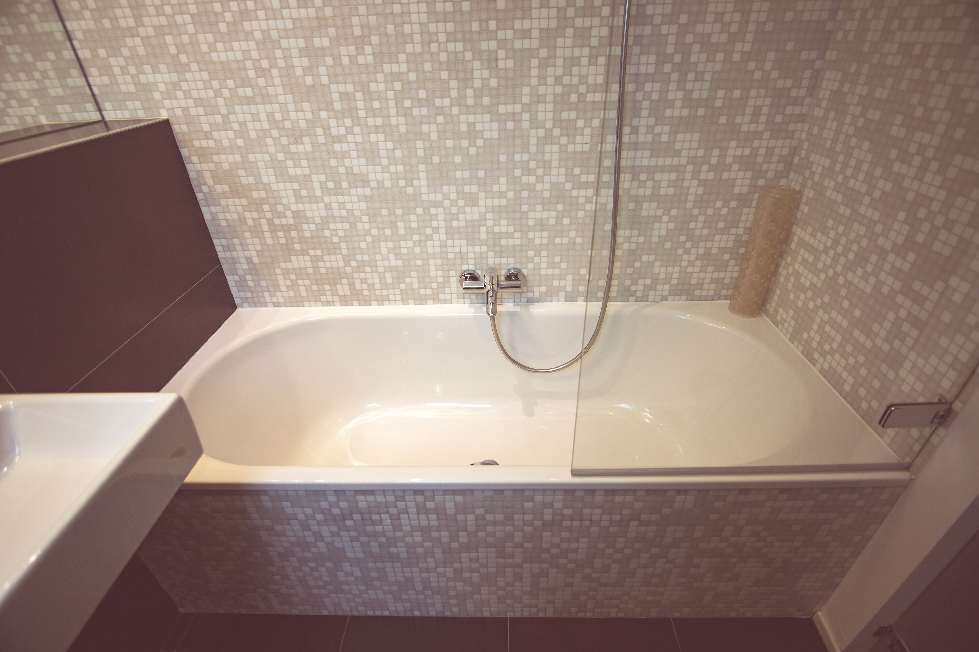 Une salle de bain moderne dotée d’une grande baignoire, d’un espace douche et d’un mur carrelé.