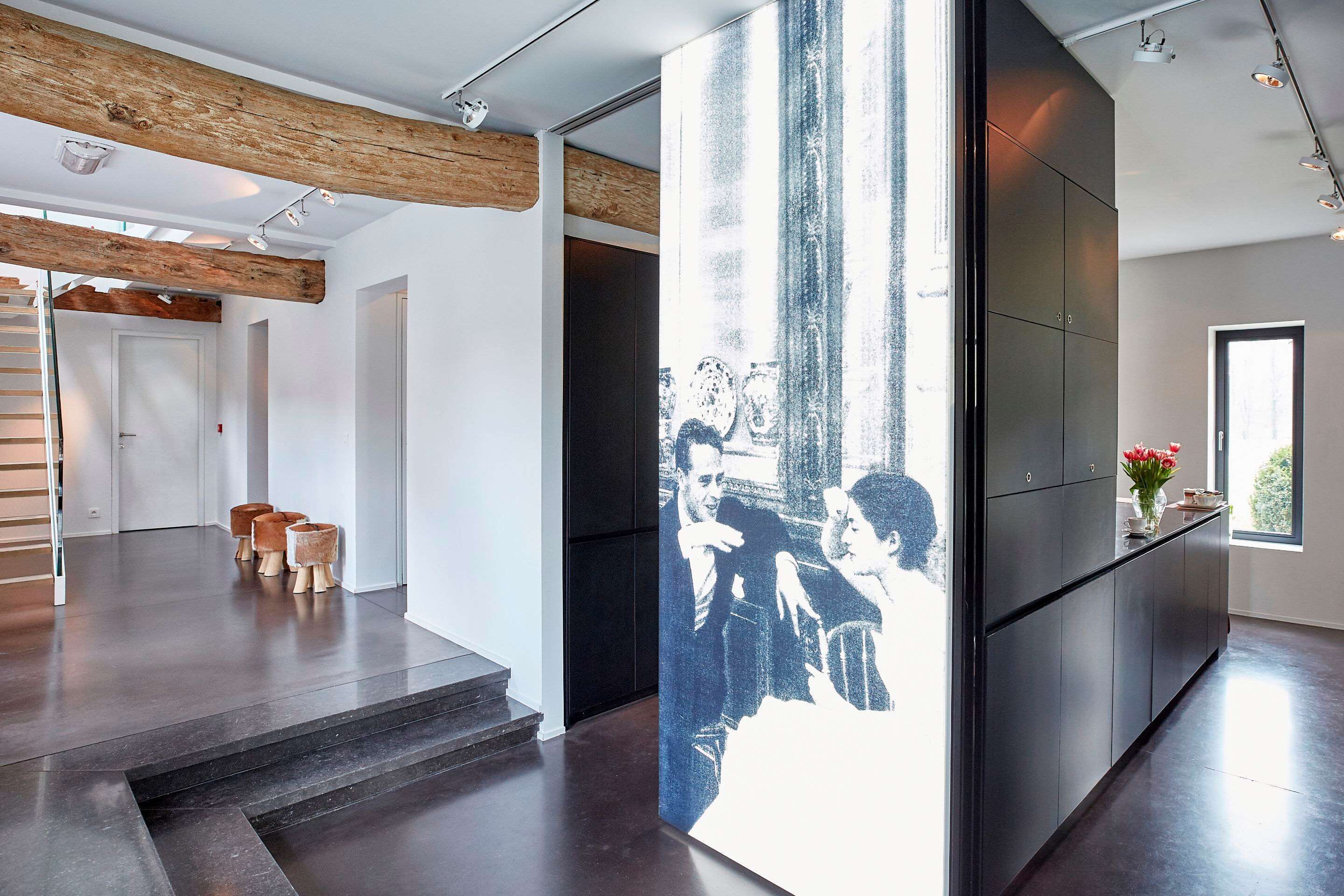 Een modern interieur met een trap, een grote zwart-wit foto en een keukenhoek.