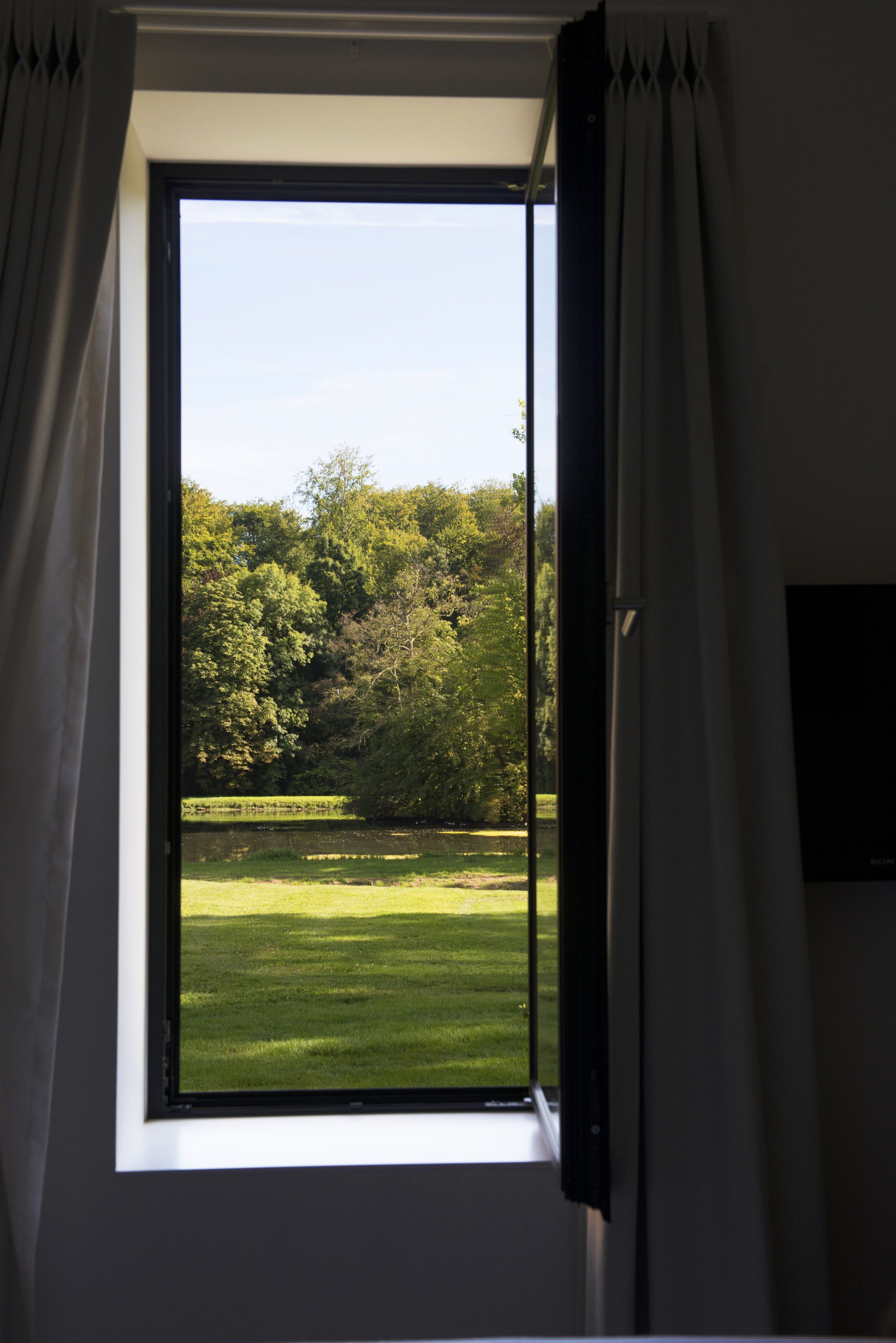 A window with a view of a grassy field and trees.