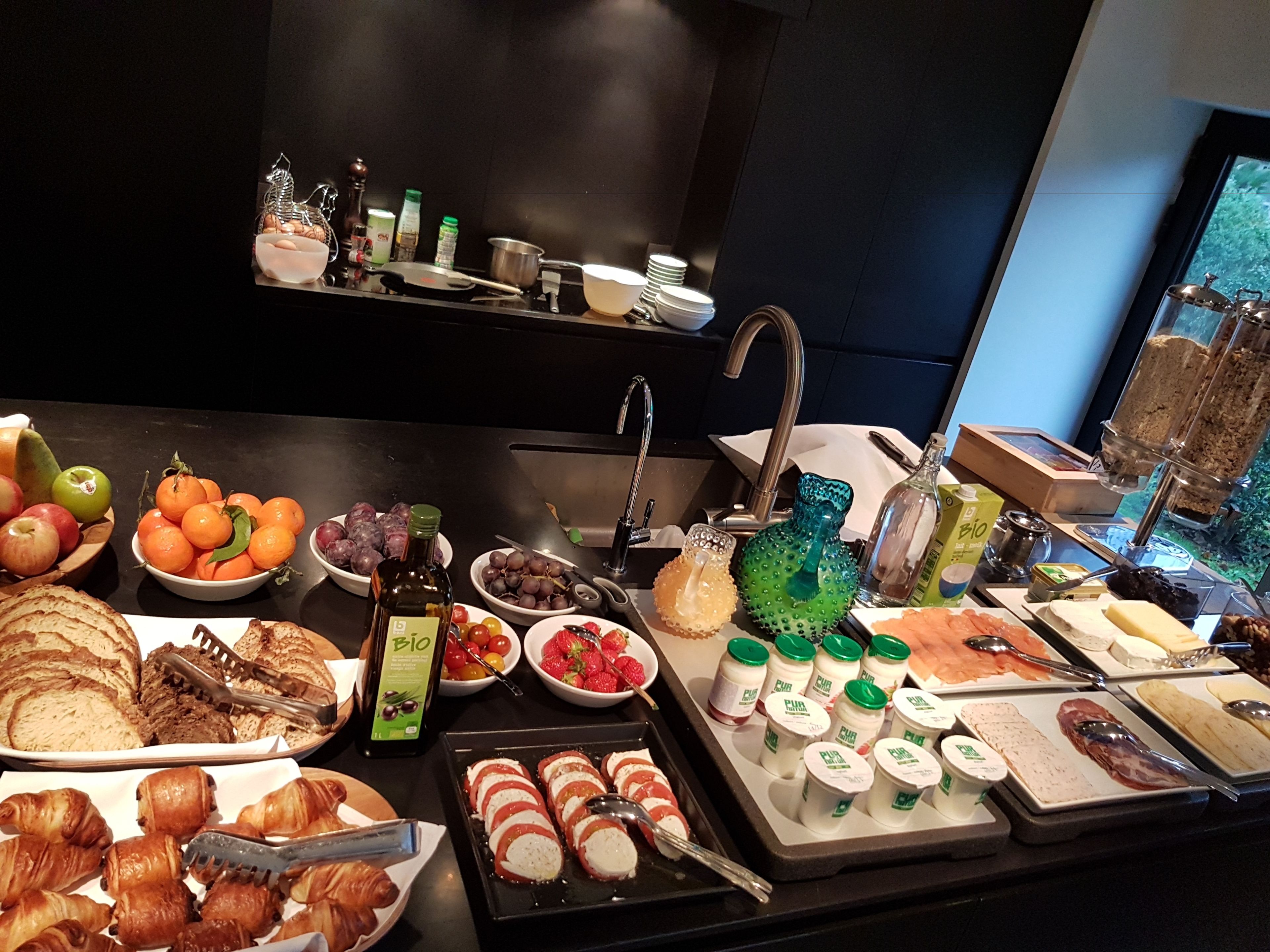 Een buffet met diverse etenswaren, zoals fruit, gebak en zuivelproducten.