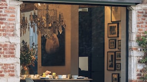 A dining area with a brick wall, a glass door, and a chandelier. - Park 7 (Huldenberg)