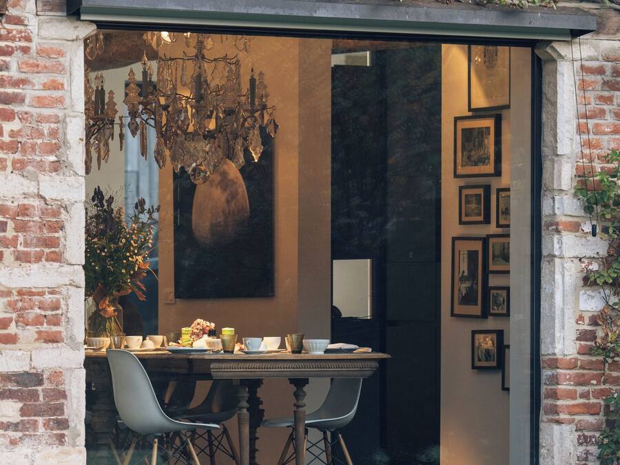 A dining area with a brick wall, a glass door, and a chandelier.