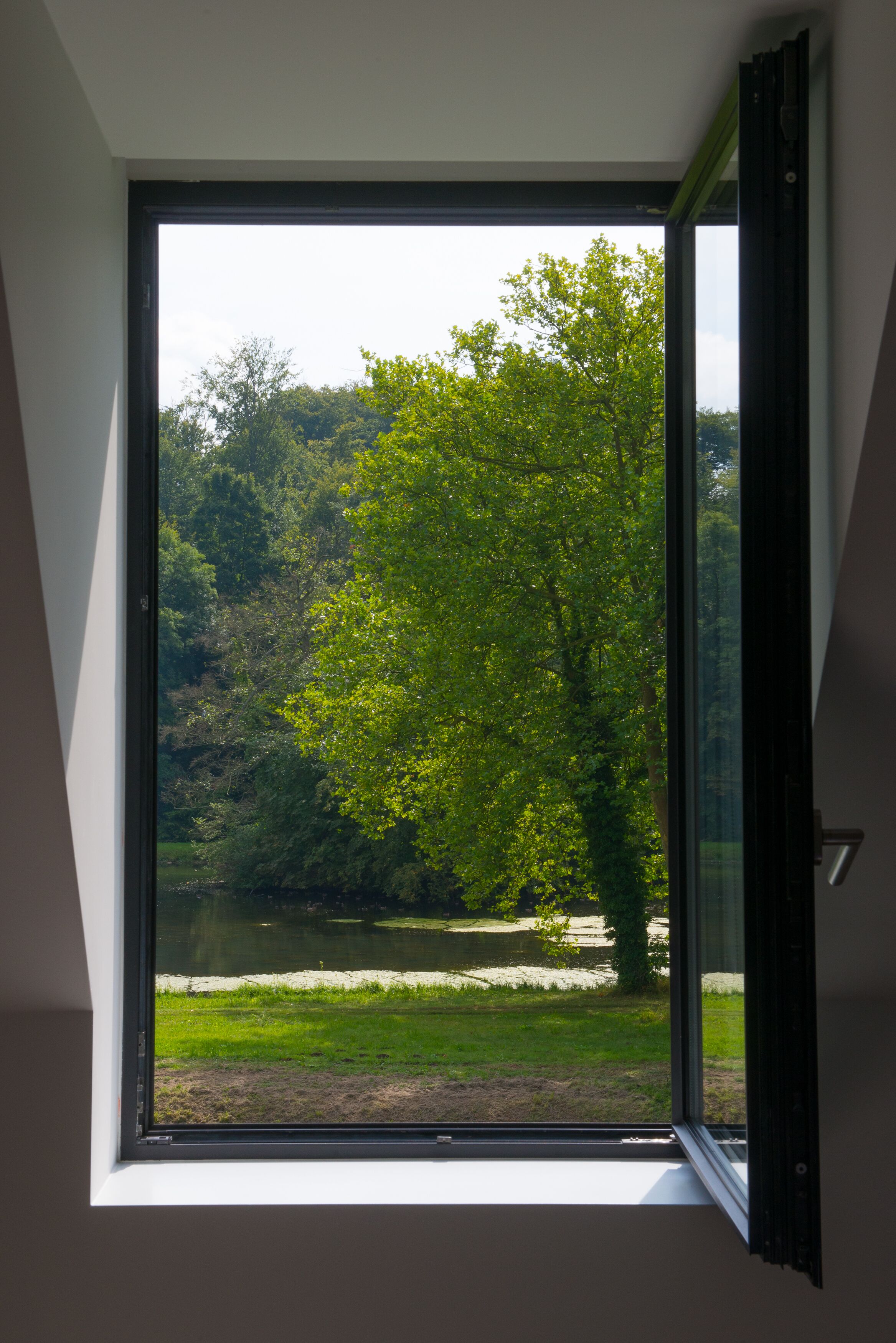 Una habitación con un amplio ventanal con vistas a un lago y un bosque.