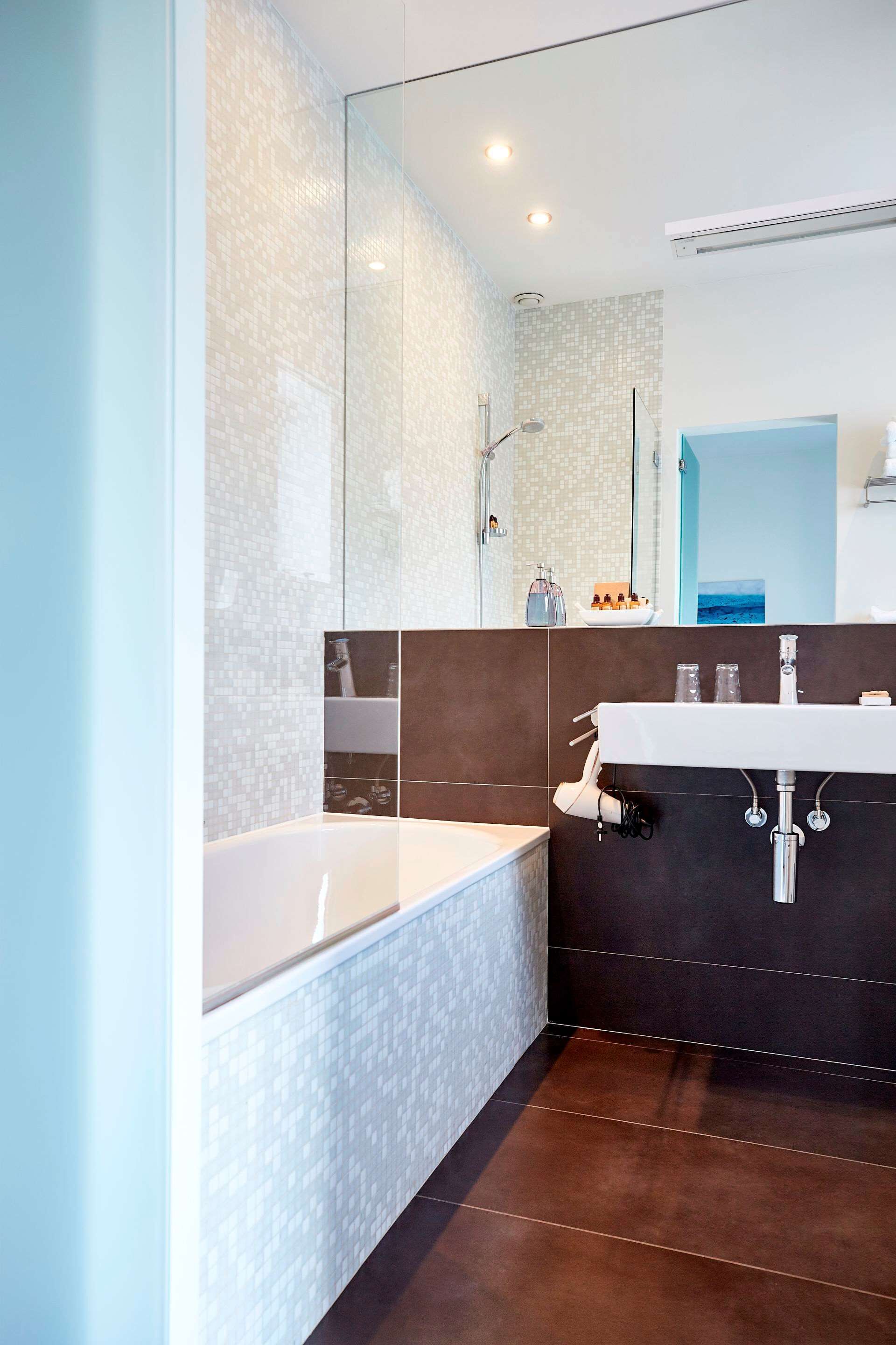 A modern bathroom with a large mirror, a bathtub, and a vanity with a sink.