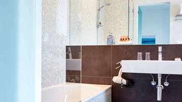A modern bathroom with a large mirror, a bathtub, and a vanity with a sink.