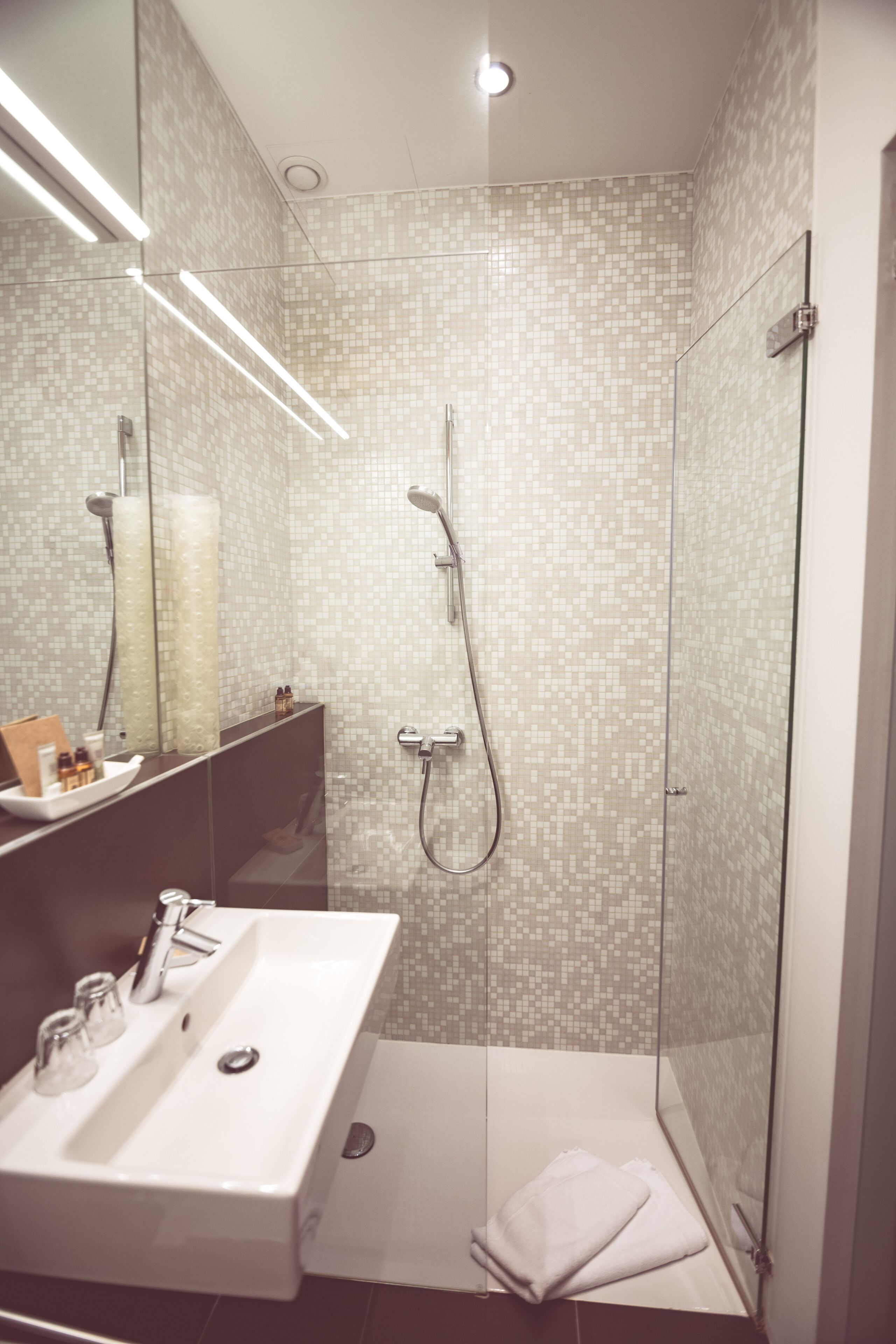 A modern bathroom with a glass-enclosed shower, a white sink, and a mirror above it.