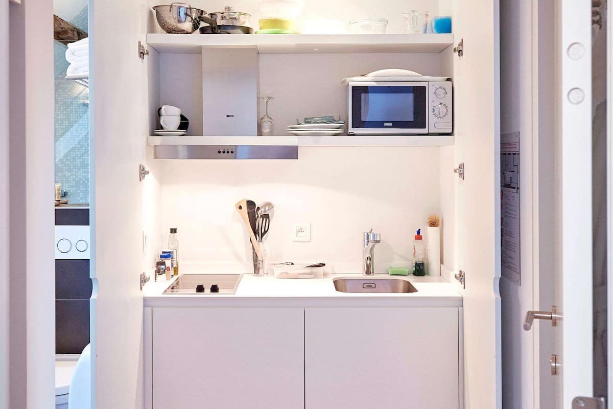 A compact kitchen with white cabinets, a microwave, and a sink.