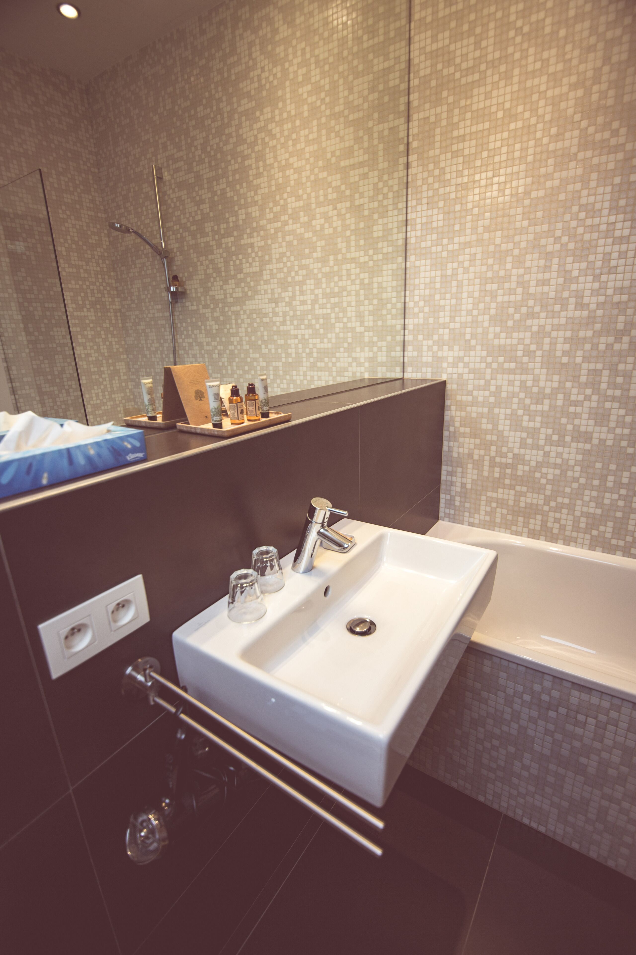 A modern bathroom with a large sink, a mirror, and a shower area.
