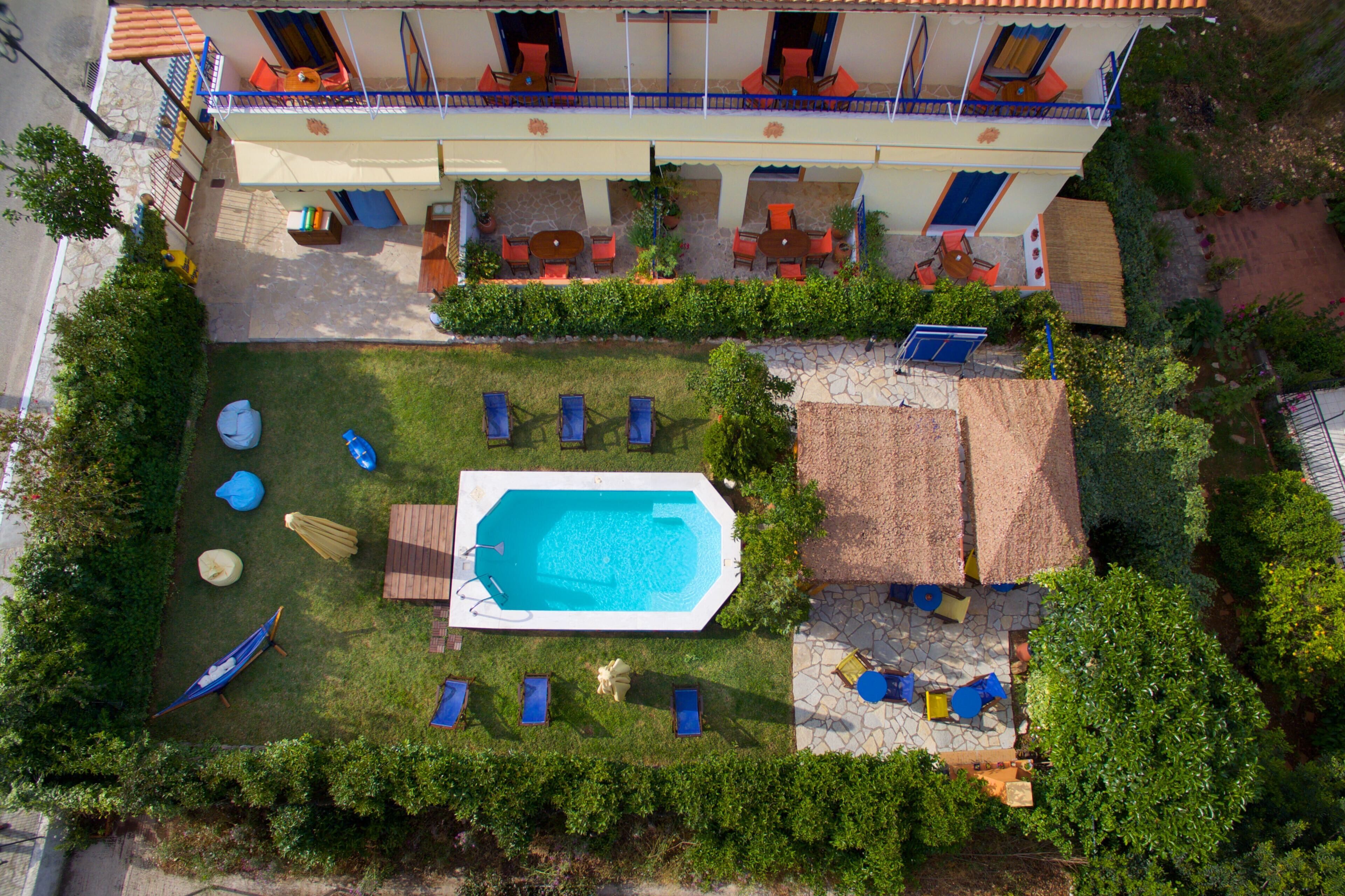 En vy från ovan av ett hotell med en swimmingpool, utomhusmöbler och en täckt uteplats.