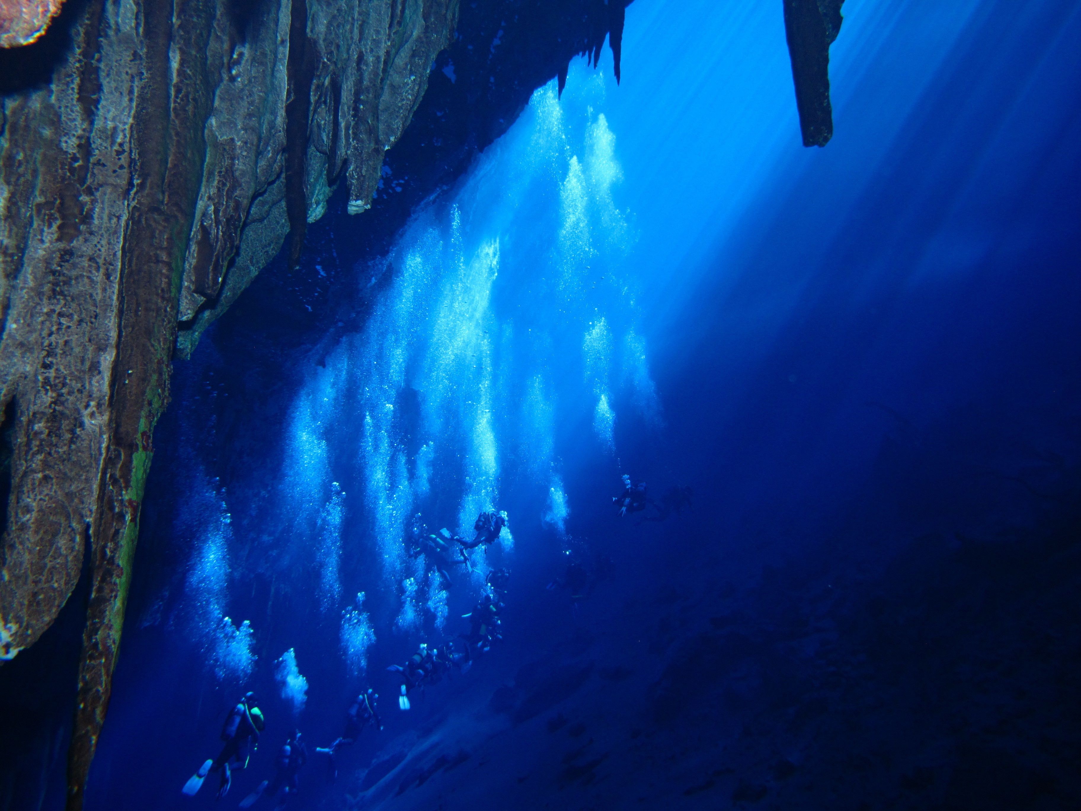 A diver exploring a cave with stalactites and stalagmites.