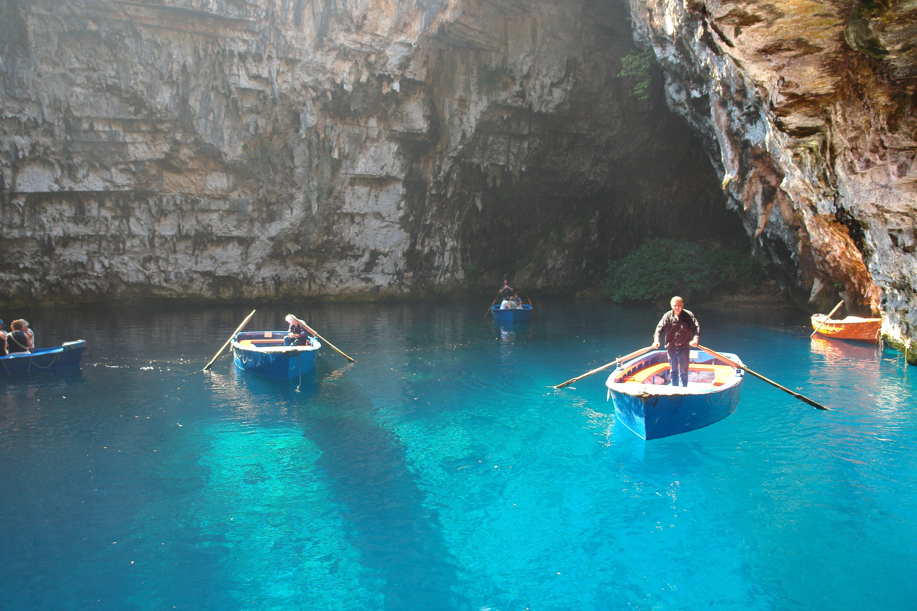 Un groupe de bateaux sur une étendue d’eau d’un bleu limpide, entourée de falaises rocheuses.