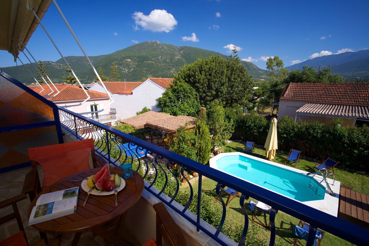 A balcony with a pool, chairs, and a table with a menu.