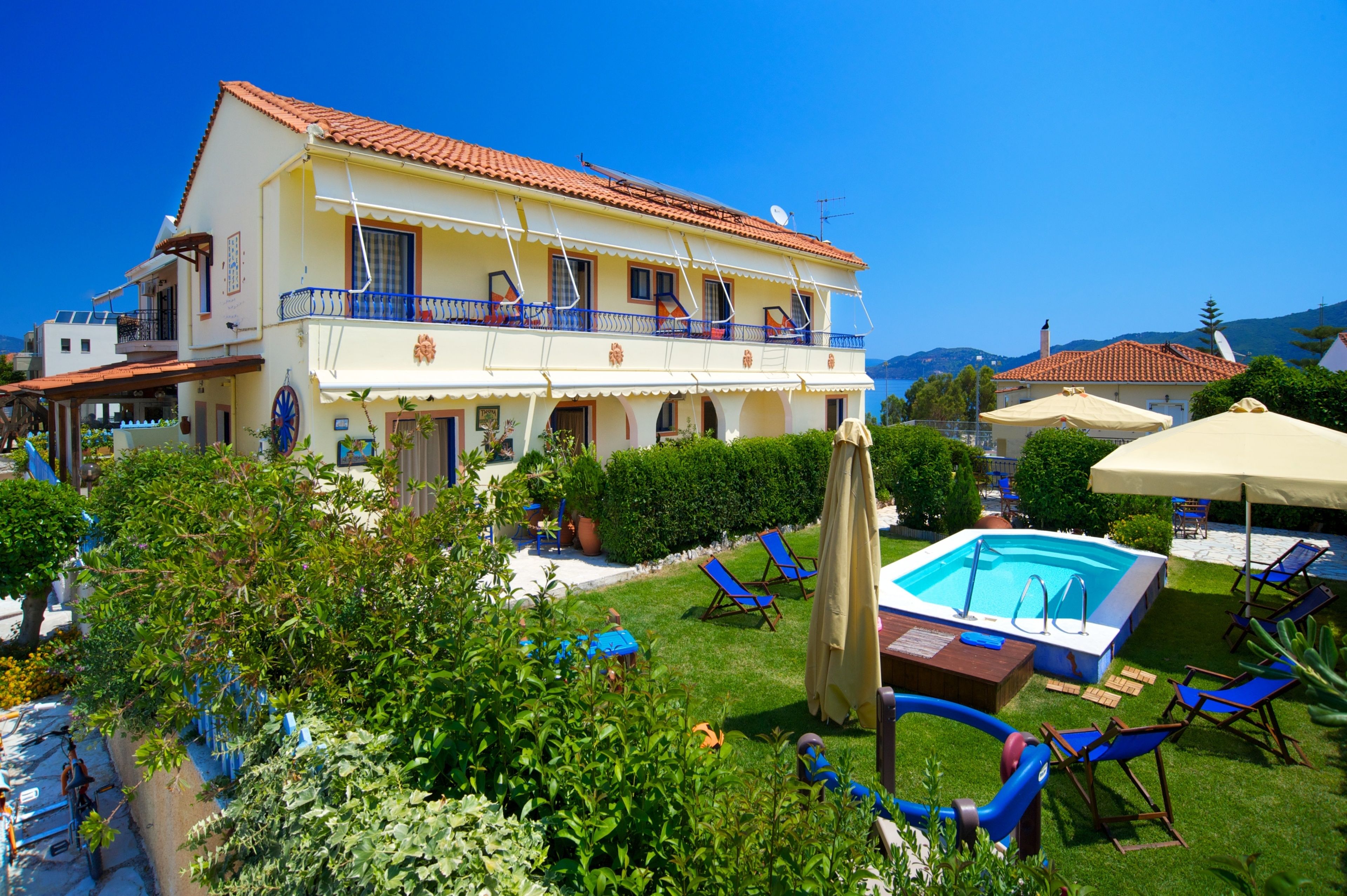 Un bâtiment à deux étages doté d’une piscine, de chaises longues bleues et de parasols.