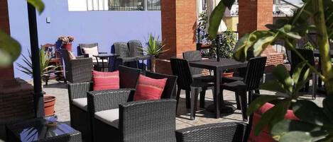 Un patio al aire libre con mobiliario de mimbre y plantas en macetas.