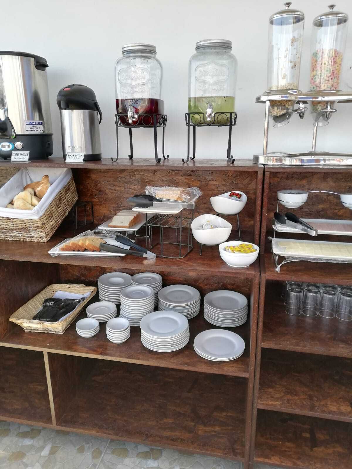 Un buffet de petit-déjeuner proposant une variété d'aliments, de boissons chaudes et d'ustensiles.