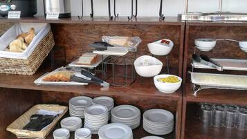 Un buffet de petit-déjeuner proposant une variété d'aliments, de boissons chaudes et d'ustensiles.