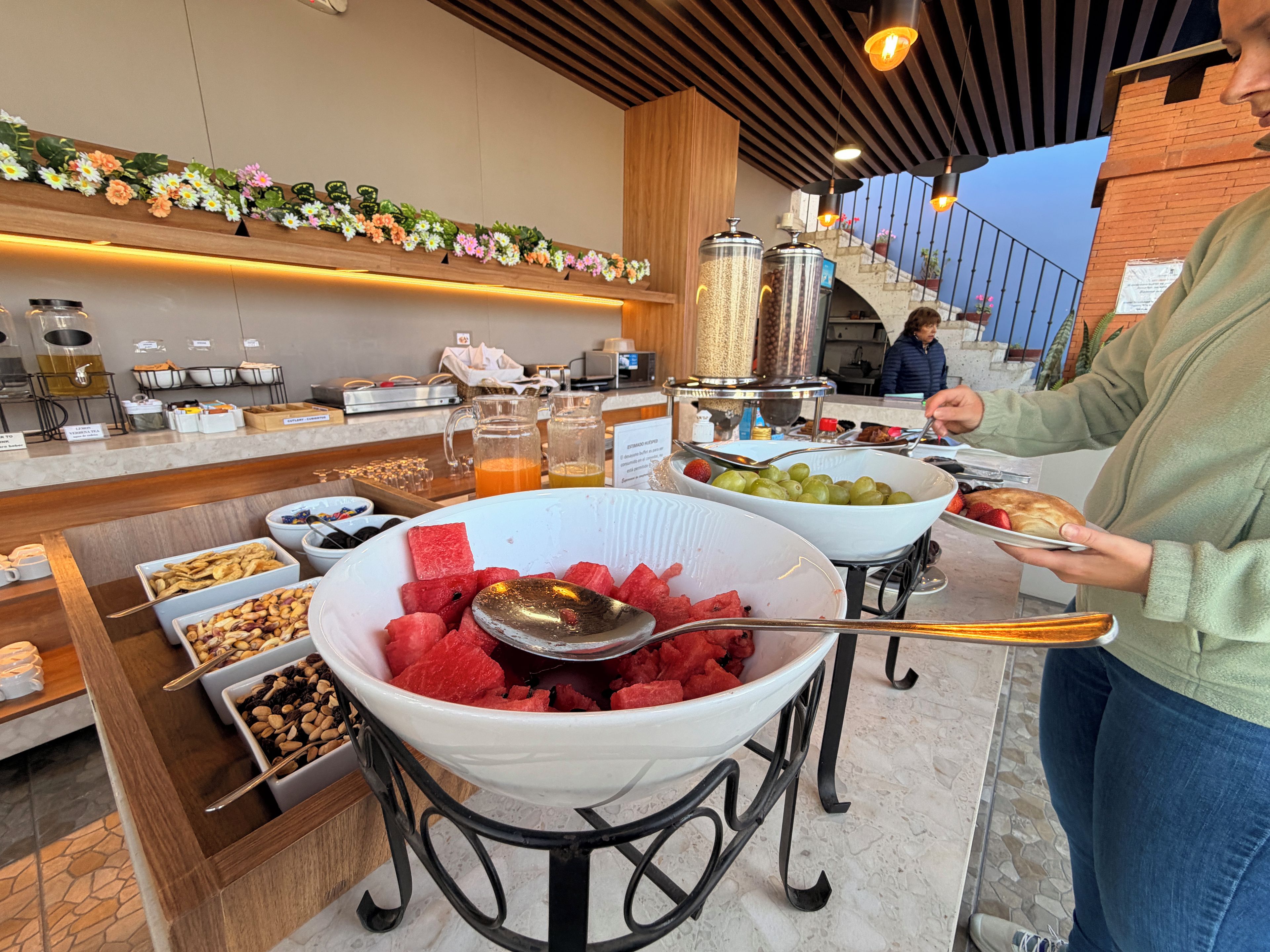 A buffet setup with various food items and a person serving themselves.